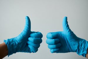 Two blue medical goved hands hold the thumbs up sign to indicate that you need to harden up