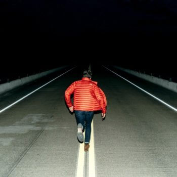 Man running in the middle of the road at night