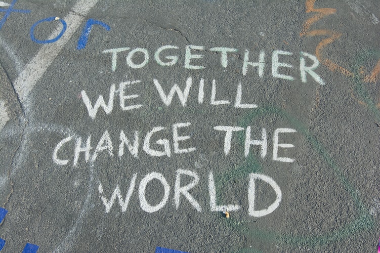 a bit of chalk is written on the sidewalk- it reads 'together we will change the world' - which is a common sentiment during this time of cultural transformation