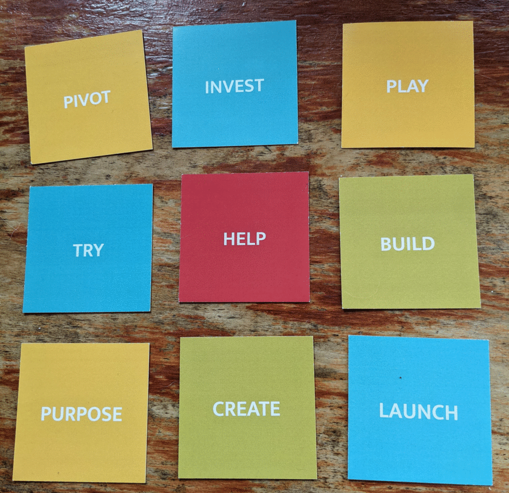 9 words are on cards. they read pivot, invest, play, try, help, build, purpose, create, launch. They are the motivational cards used to inspire the launch of a marketing for small business, social enterprise and startup project via Patreon by Unashamedly Creative.