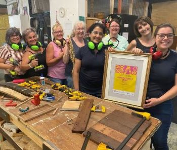 a smiling group of women in a workshop make up Parramatta Women's Shed